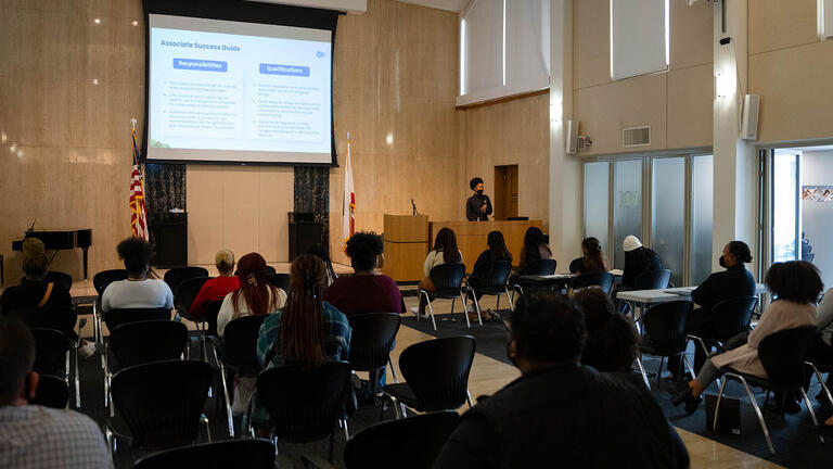 Speaker presents to a room full of students at BASE event.