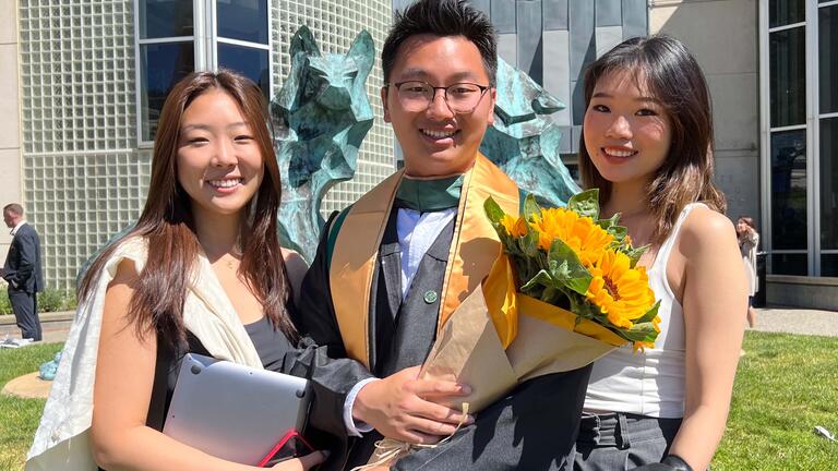 Graduate poses with flowers and friends.