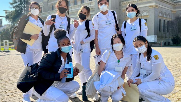 Nursing students in scrubs gather for photo