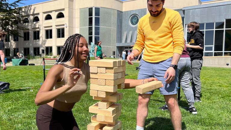 Two students play with a giant Jenga tower