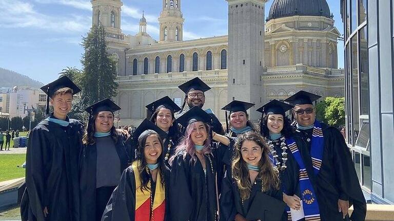 Ten School of Education graduates stand in front of St. Ignatius Church.