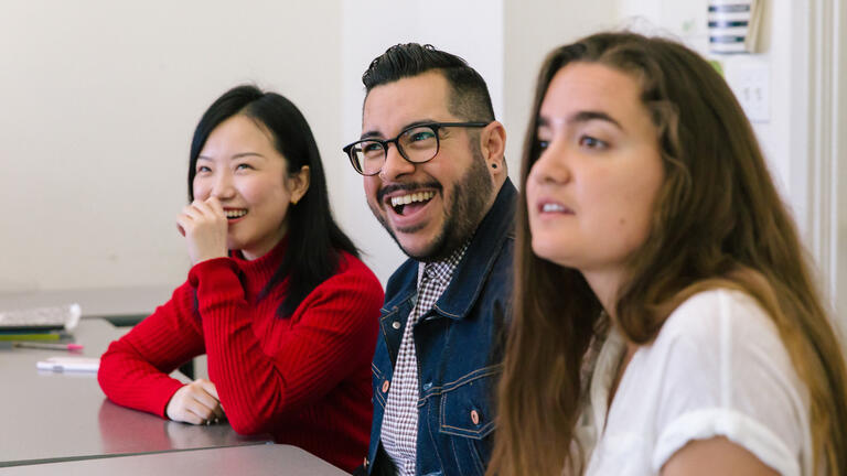 Two students sitting in a classroom laughing.