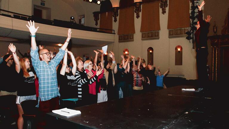 Students standing up with their hands in the air