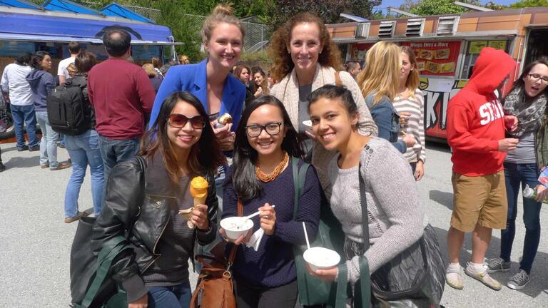 Five students posing for picture holding takeout containers of food