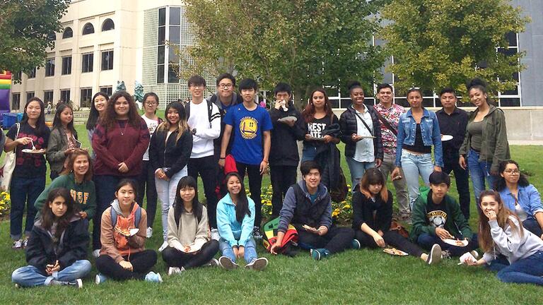 Students pose for a photo on the lawn near the library.
