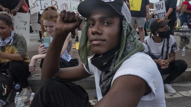 African American man sits in protest with fist raised