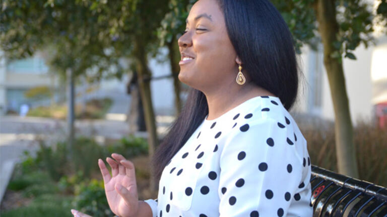 Breniel Lemley sitting on a bench on USF's campus, in the middle of speaking