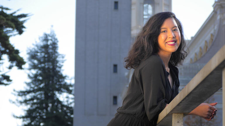 Kimberlin Borca smiling at the camera, leaning on a staircase railing