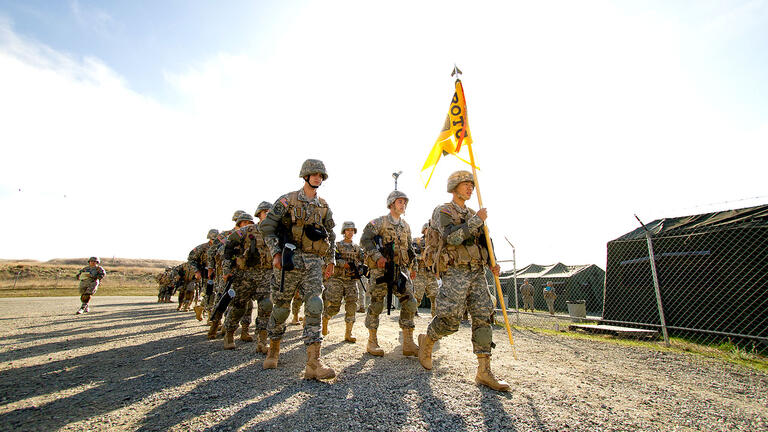 ROTC holding a flag and marching