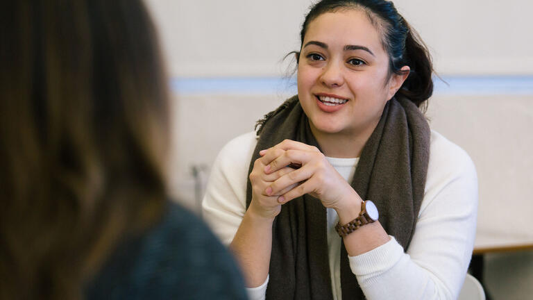 Student speaks in classroom to a colleague.