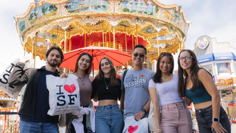 Six students standing in front of the Pier 39 carousel