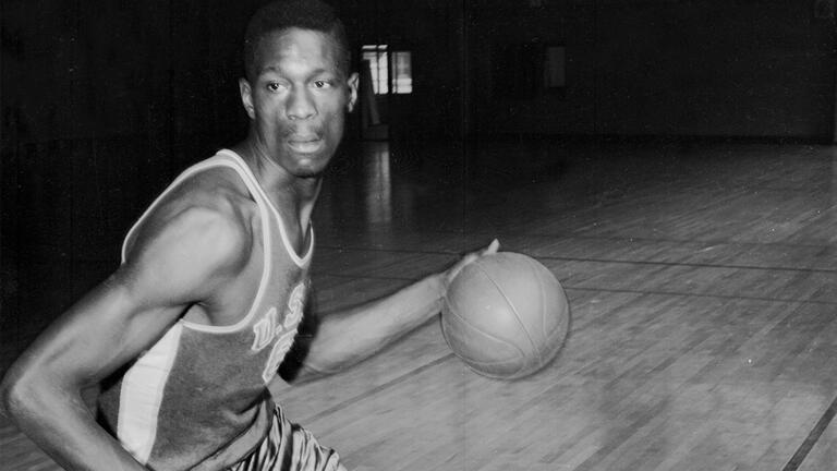 Bill Russell dribbling on a court.