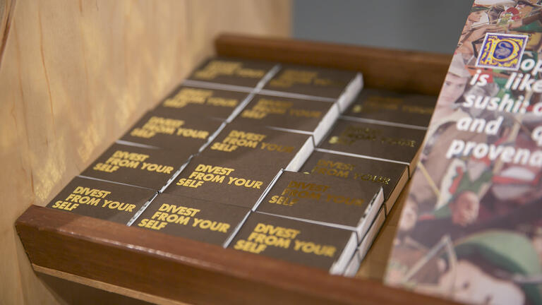 Matchboxes with "divest from your self" written on them.