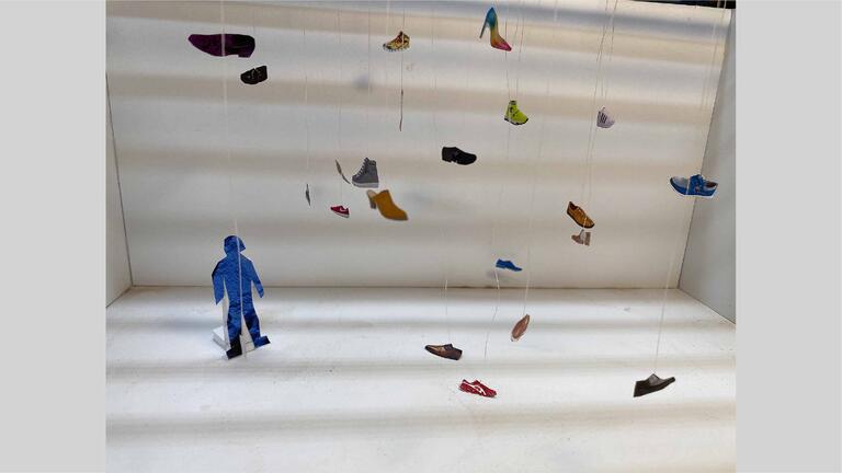 Picture cut-outs of shoes hung up by wire, small standee of a silhouette in the corner