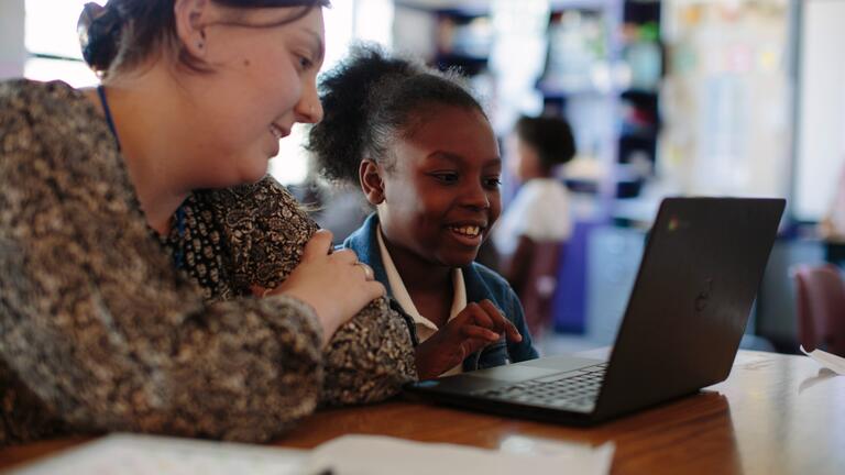 Student next to a child on a computer