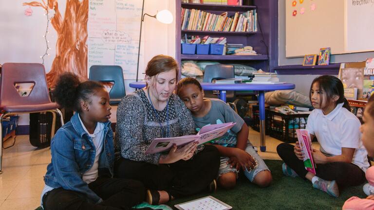 Student reading to children in a classroom