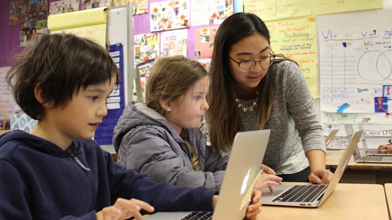 Student helping two children with their computers