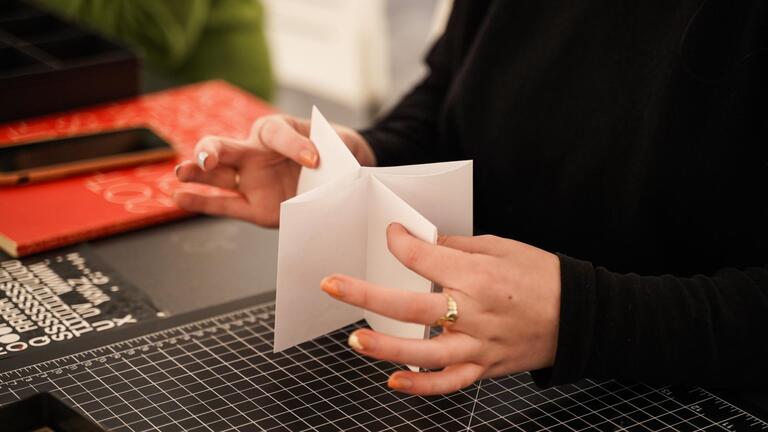 hands folding a zine