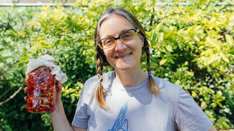 Novella Carpenter smiling and holding a jar outside