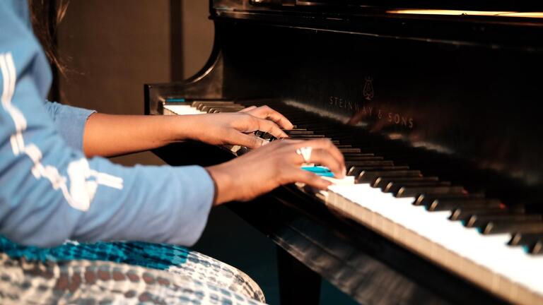 close up of student musician&#039;s hands playing piano 