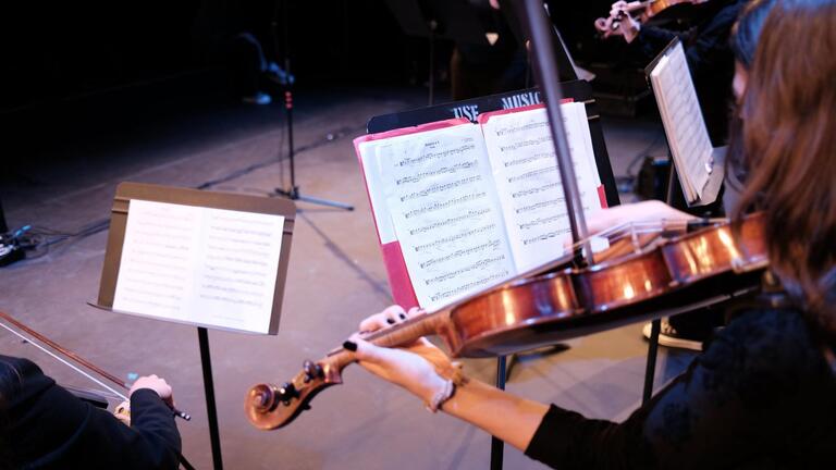 student musician playing the violin and looking at sheet music