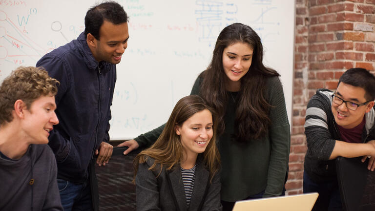 Students sitting at a table with their laptops.