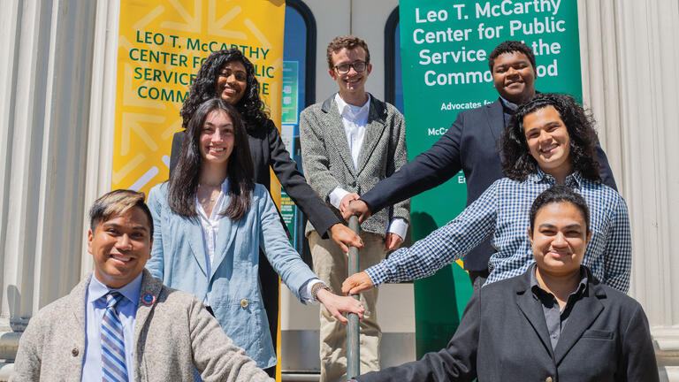 A group of students line up on a staircase in front of McCarthy Center banners.