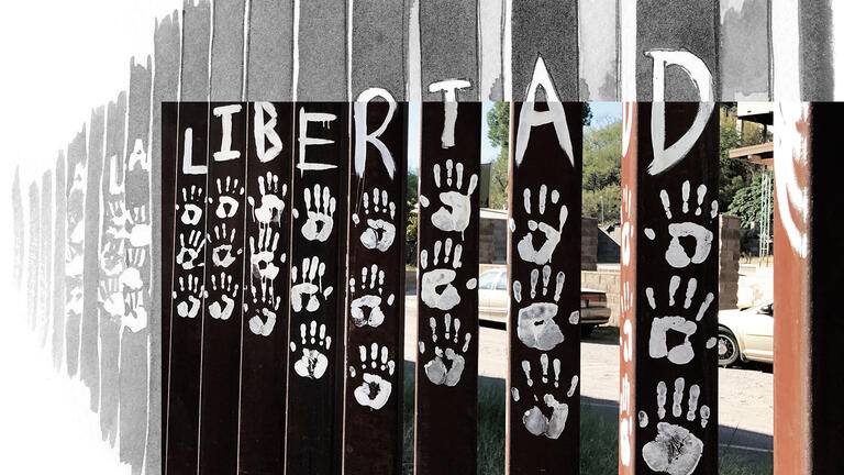 Photo and illustration of U.S.-Mexico border wall with hand prints and \"La Libertad\" painted on