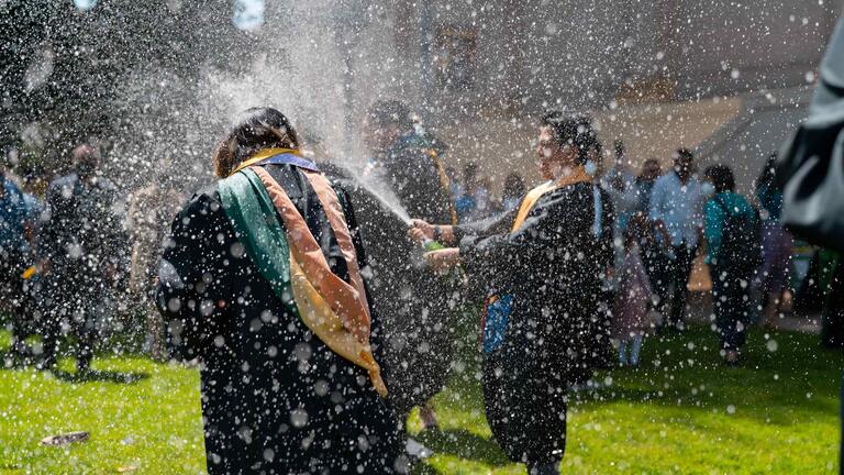 USF students popping a champagne bottle at graduation