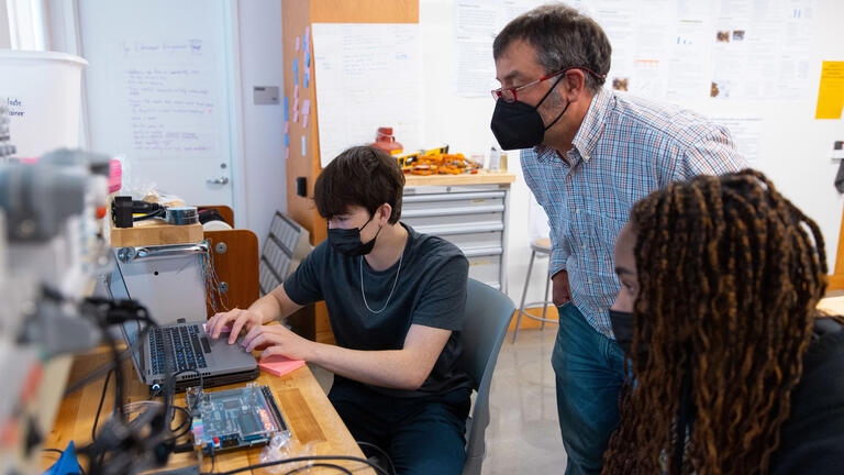 Two students showing professor project on laptop screen