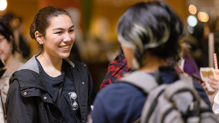 two students talking together during an event