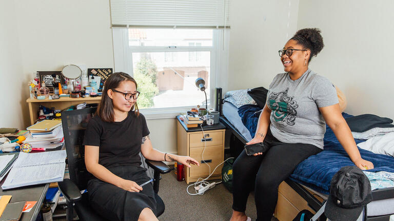 Two students facing each other in a dorm room