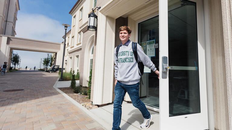 USF student exiting residence hall on Lone Mountain