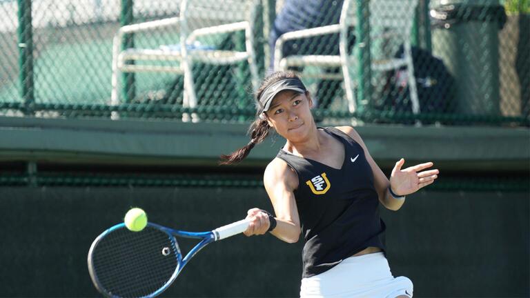 USF women&#039;s tennis player mid-hitting a tennis ball