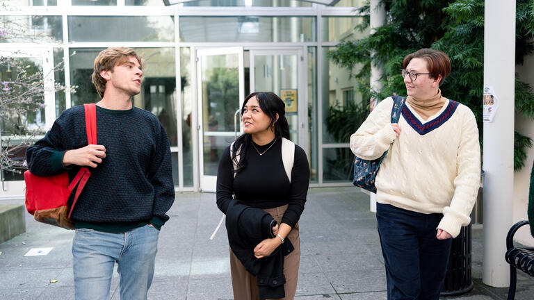 Three students walking on campus.