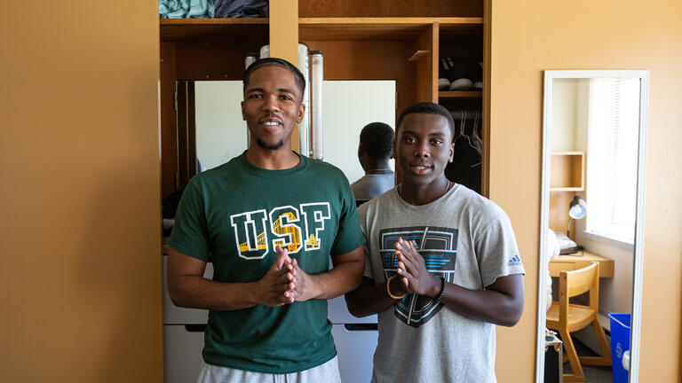 two students standing together in a dorm