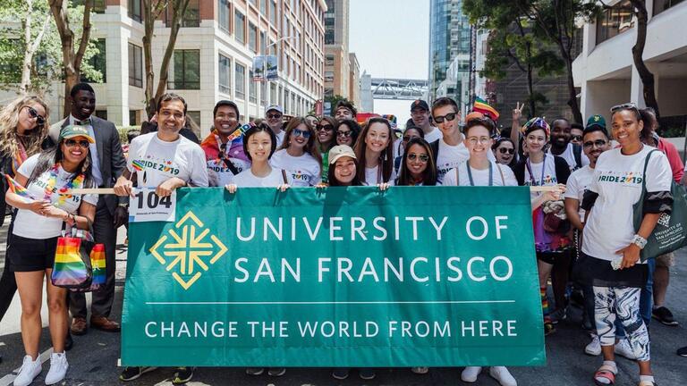 USF community members holding a sign reading University of San Francisco — Change the world from here