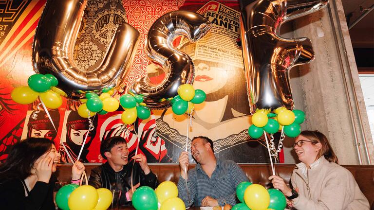 Alumni laughing and holding USF balloons