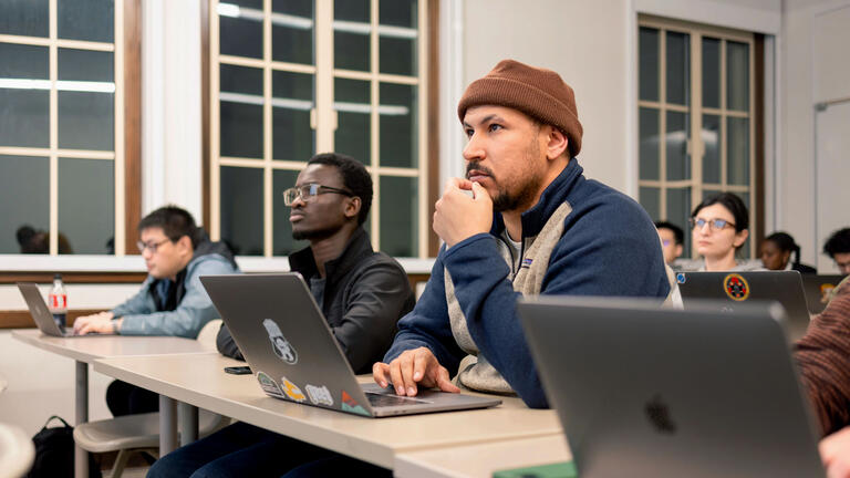 Students in a classroom looking at a laptop