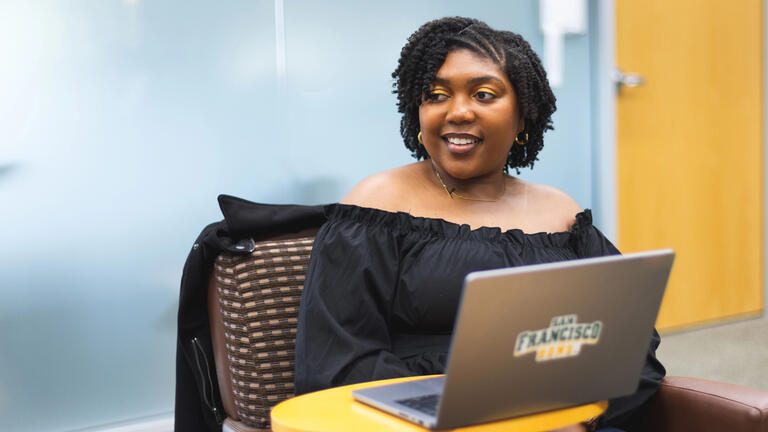 USF student smiling, sitting in front of laptop