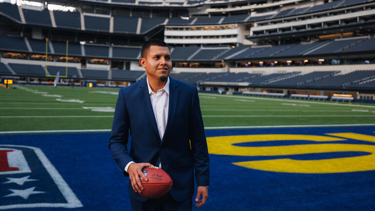 Sport Management student on a field holding a football