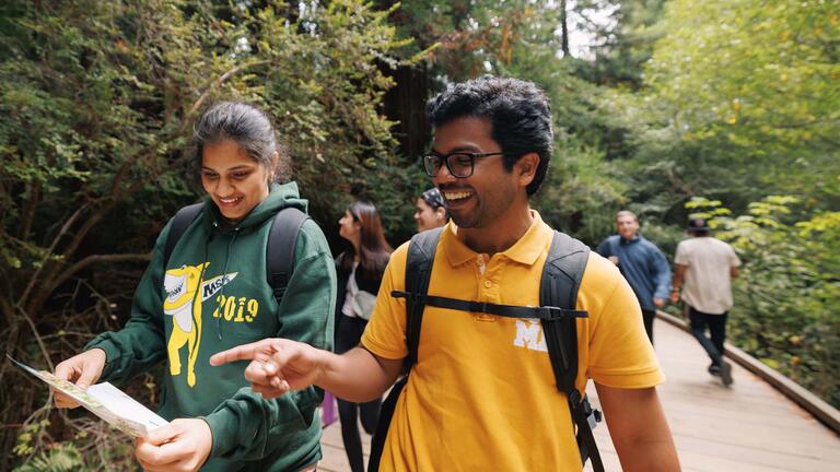 Two students walking and looking at a map