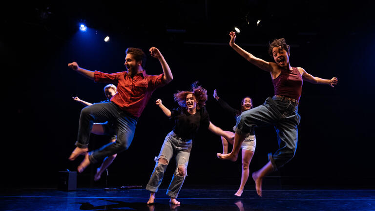 students in a mid-air jump during a dance performance