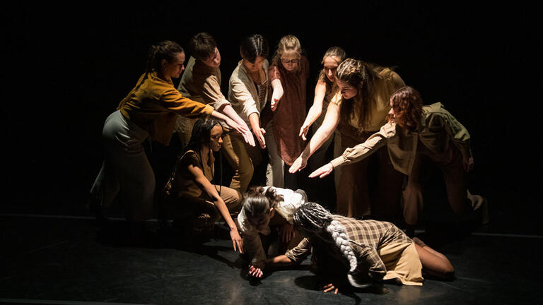 a group points at a couple on the ground during a dance performance