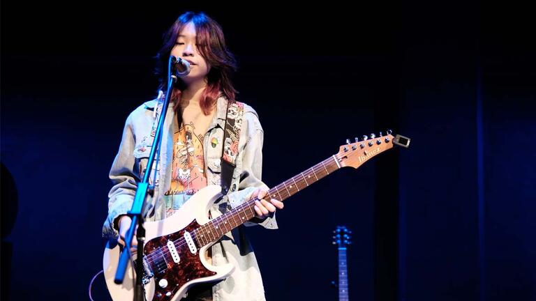 girl plays guitar in during a performance