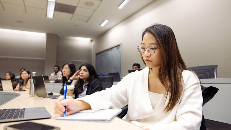 students writes on notebook during class