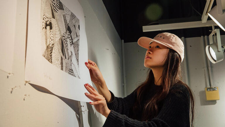 USF student mounting illustration on gallery wall