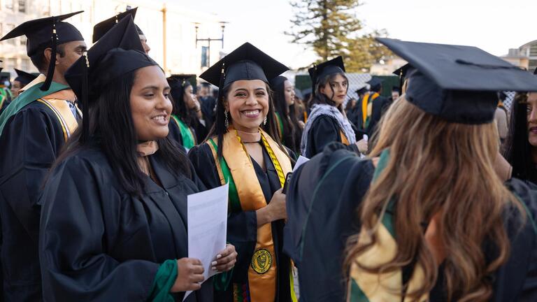 students gathered on campus wearing graduation gowns