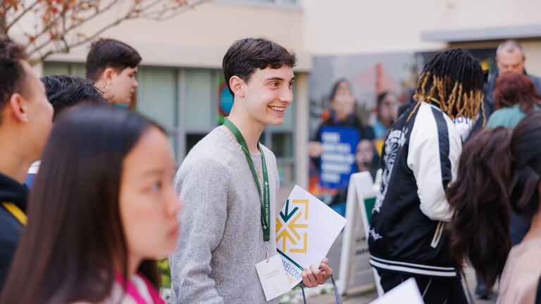 student worker holds clipboard at event