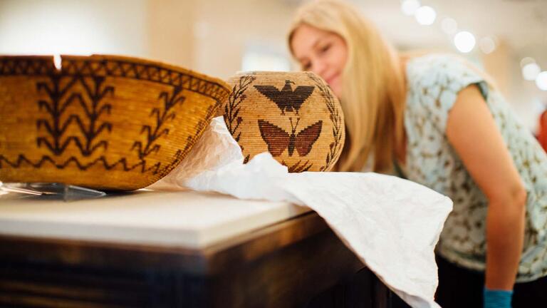 Student wearing gloves handling artifacts.